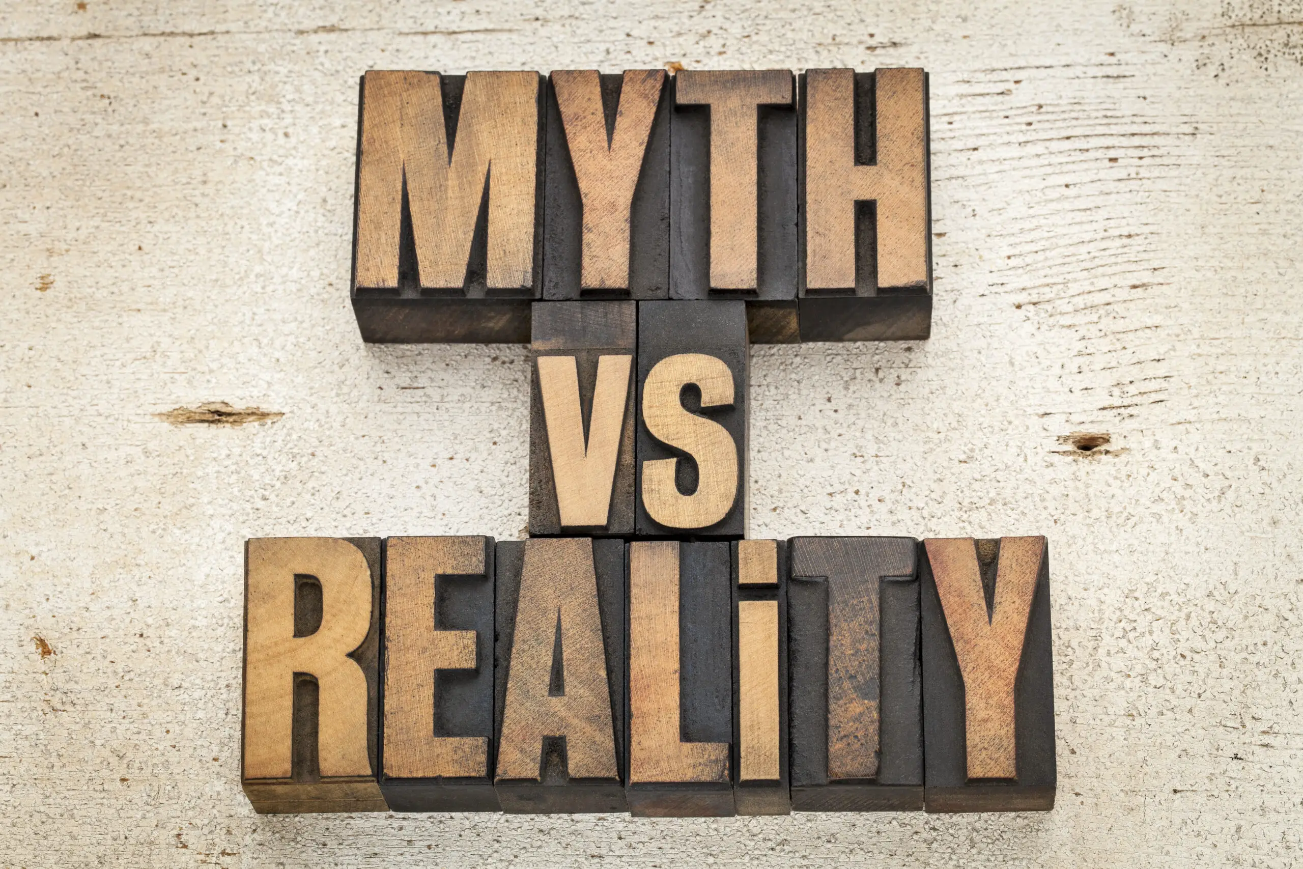 myth versus reality - concept in vintage letterpress wood type on a grunge painted barn wood background