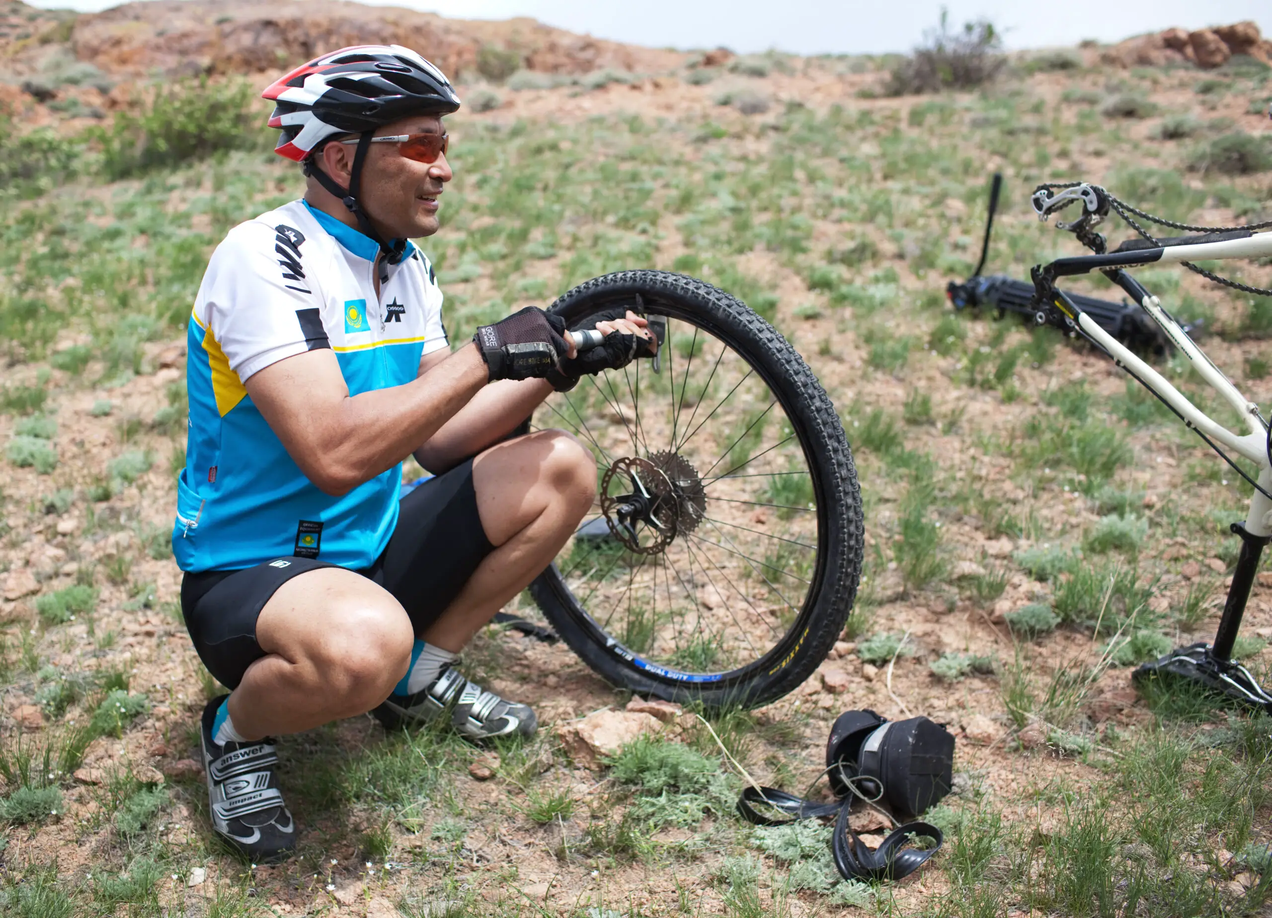 Biker changing a flat tire on desert mountain bike competition