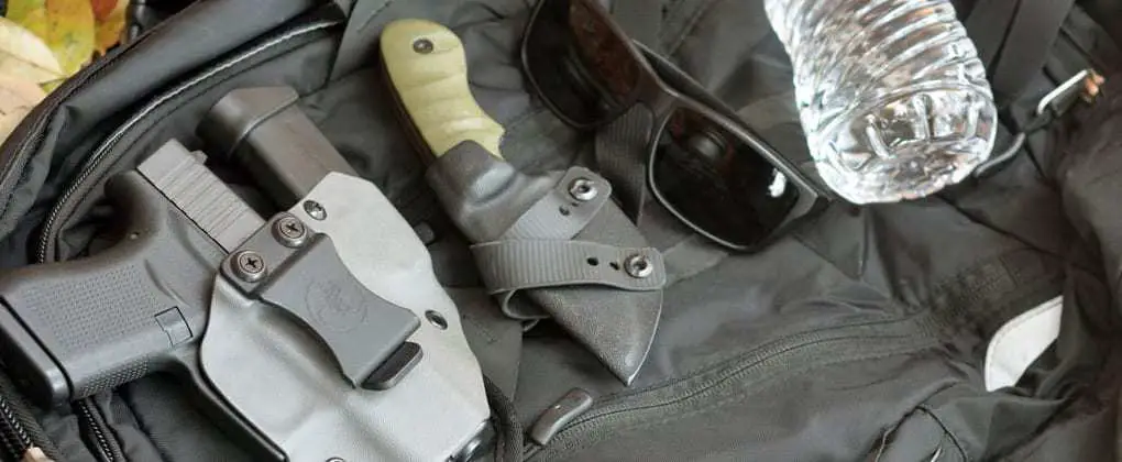 glock 43 in alex and ryan design master blaster holster, with boker ridgeback fixed blade knife, sunglasses, and a bottle of water.